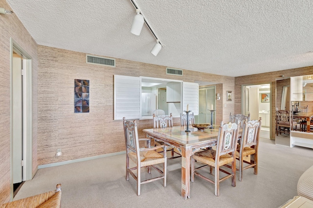 dining area with light colored carpet and a textured ceiling