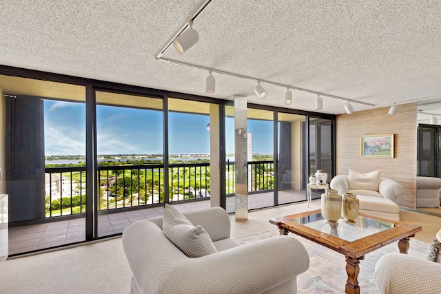 living room with track lighting, a textured ceiling, and a wall of windows