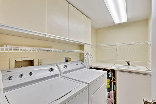 laundry area with washing machine and clothes dryer, cabinets, and sink