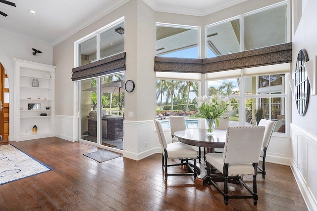 dining room with ornamental molding, a towering ceiling, dark wood-type flooring, and built in features