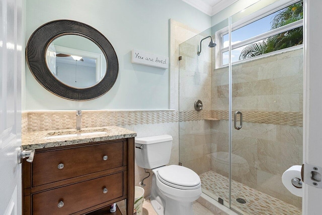 bathroom featuring tile walls, a shower with shower door, vanity, crown molding, and toilet