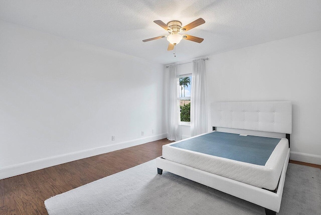 bedroom with ceiling fan, a textured ceiling, and dark hardwood / wood-style flooring