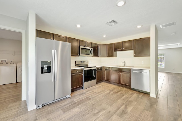 kitchen with light wood-type flooring, washer and dryer, sink, stainless steel appliances, and dark brown cabinetry