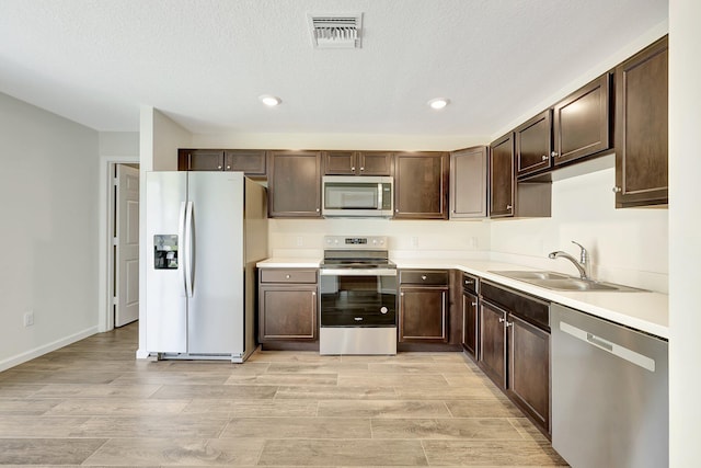 kitchen featuring dark brown cabinetry, light hardwood / wood-style floors, sink, and stainless steel appliances