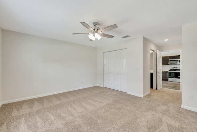 unfurnished bedroom featuring ceiling fan, light colored carpet, and a closet