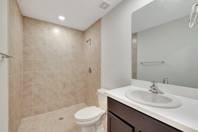 bathroom featuring tiled shower, vanity, toilet, and tile patterned flooring