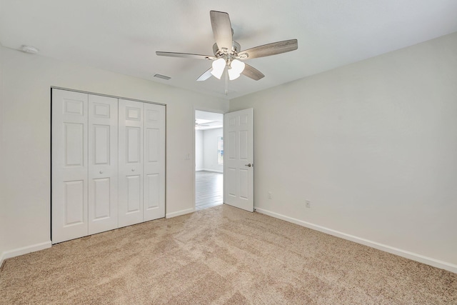 unfurnished bedroom with light carpet, a closet, and ceiling fan