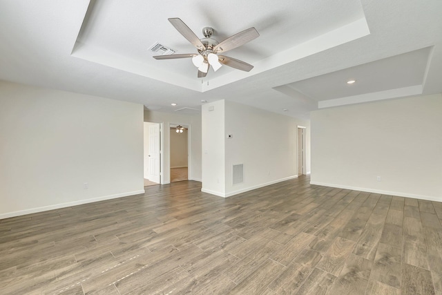 spare room with ceiling fan, hardwood / wood-style flooring, and a raised ceiling