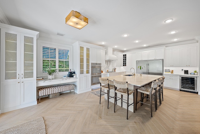 kitchen featuring appliances with stainless steel finishes, custom exhaust hood, light parquet floors, sink, and wine cooler