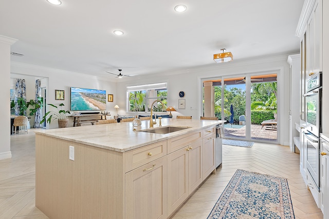 kitchen featuring stainless steel appliances, ceiling fan, a kitchen island with sink, crown molding, and sink