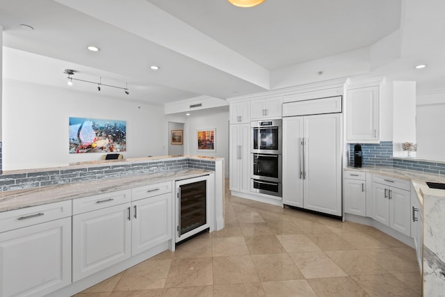 kitchen featuring light stone counters, white cabinets, tasteful backsplash, beverage cooler, and stainless steel appliances