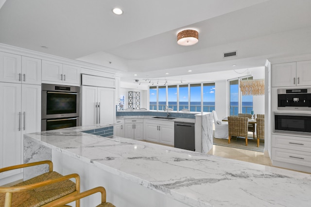 kitchen with kitchen peninsula, white cabinetry, stainless steel appliances, a breakfast bar, and a water view