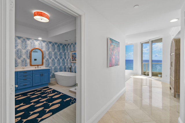 bathroom featuring crown molding, a water view, a bathing tub, and vanity