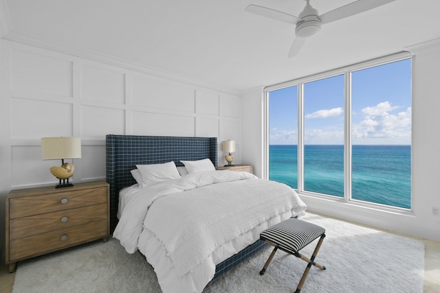 bedroom with light carpet, a water view, and ceiling fan