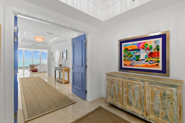 corridor with a raised ceiling, light tile patterned floors, and a water view