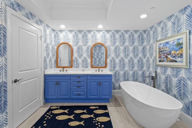 bathroom featuring vanity, crown molding, a tray ceiling, hardwood / wood-style flooring, and a washtub