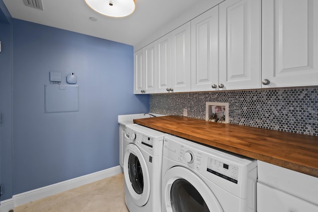 laundry room featuring cabinets, light tile patterned floors, and separate washer and dryer