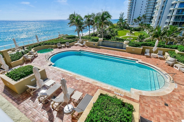 view of pool featuring a water view and a patio area