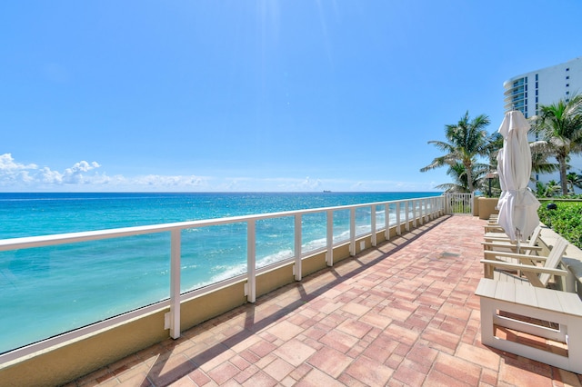 balcony featuring a view of the beach and a water view