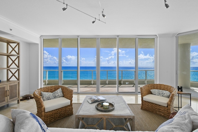 living room featuring floor to ceiling windows, a water view, and rail lighting