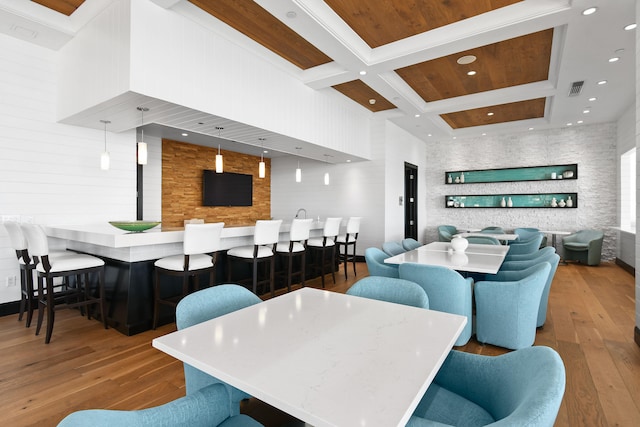 dining space with coffered ceiling, beam ceiling, hardwood / wood-style floors, and a high ceiling