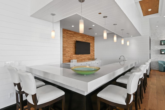 bar with wooden walls, hanging light fixtures, and hardwood / wood-style floors