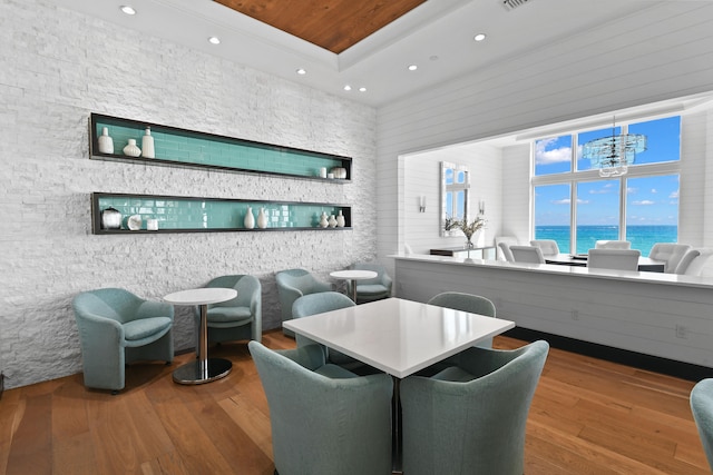 dining area featuring wood-type flooring, a notable chandelier, and a water view