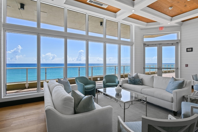 living room featuring a water view, light hardwood / wood-style flooring, french doors, and plenty of natural light