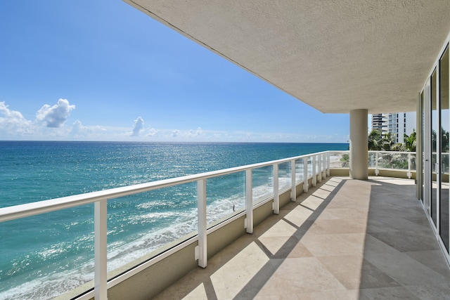 balcony featuring a water view and a beach view