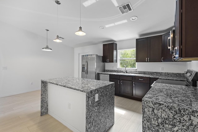 3848 NW 19th Ave, Okeechobee, FL 34972 - kitchen featuring stainless steel appliances, a kitchen island, dark stone countertops, dark brown cabinets, and hanging light fixtures