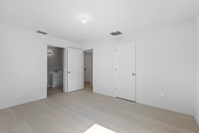 3848 NW 19th Ave, Okeechobee, FL 34972 - unfurnished bedroom featuring light wood-type flooring, ensuite bath, and baseboards