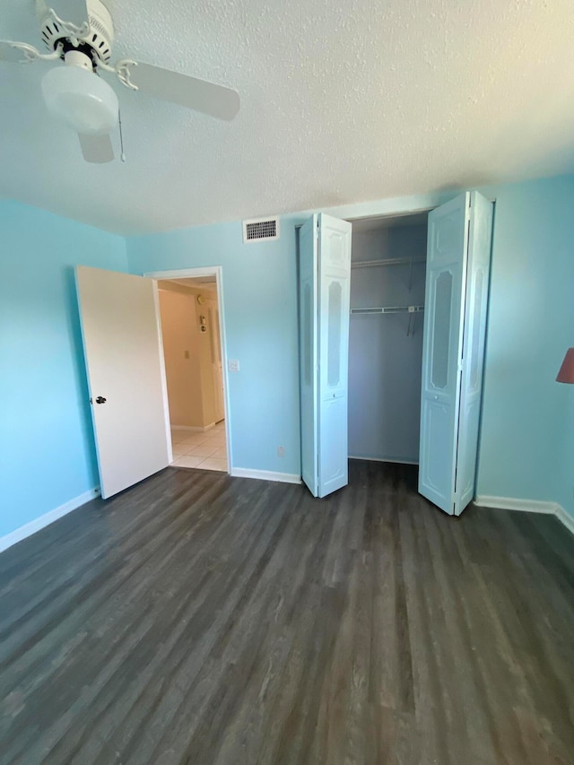 unfurnished bedroom with a textured ceiling, dark hardwood / wood-style floors, a closet, and ceiling fan