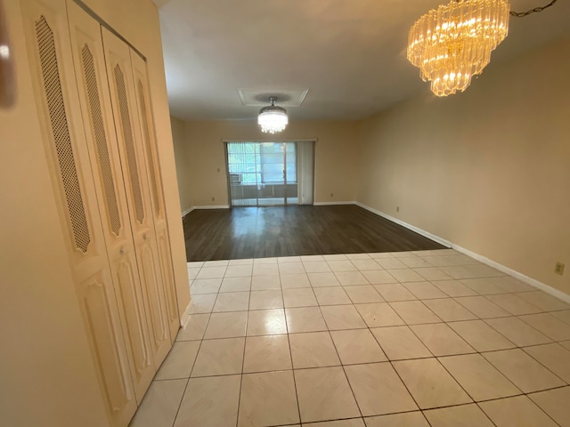 empty room featuring a notable chandelier and light wood-type flooring