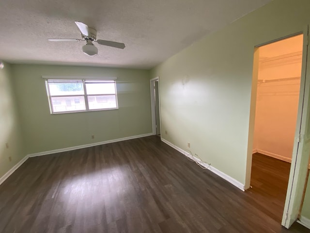 empty room featuring a textured ceiling, dark hardwood / wood-style floors, and ceiling fan