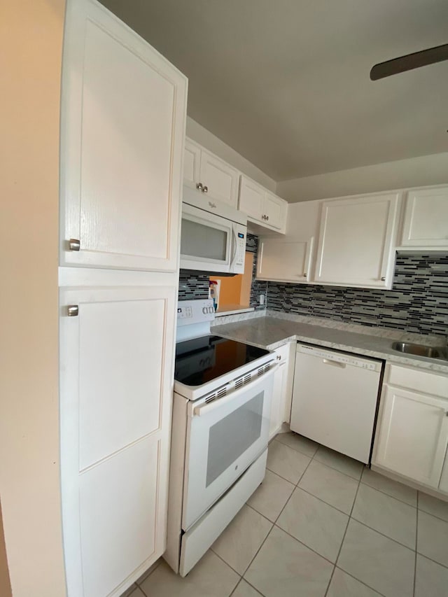 kitchen with backsplash, sink, light tile patterned flooring, white cabinets, and white appliances