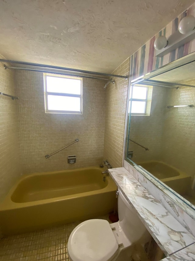 full bathroom featuring vanity, toilet, a healthy amount of sunlight, and tiled shower / bath