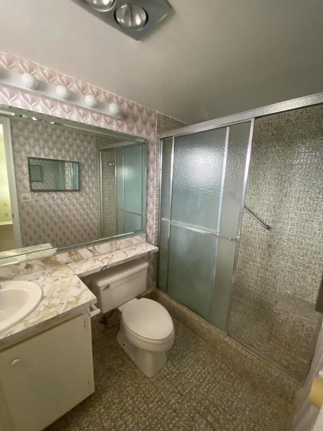 bathroom featuring vanity, a shower with shower door, and toilet