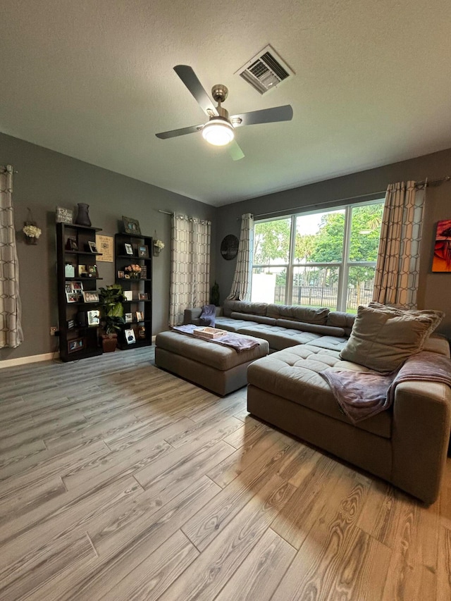 living room with light hardwood / wood-style floors, a textured ceiling, and ceiling fan