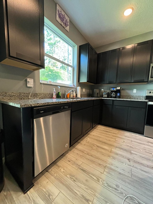 kitchen with light hardwood / wood-style floors, a textured ceiling, stainless steel appliances, and light stone counters