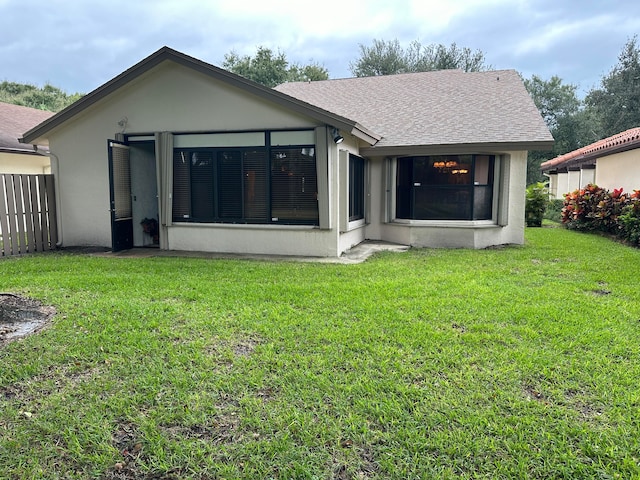 rear view of house with a yard and a sunroom