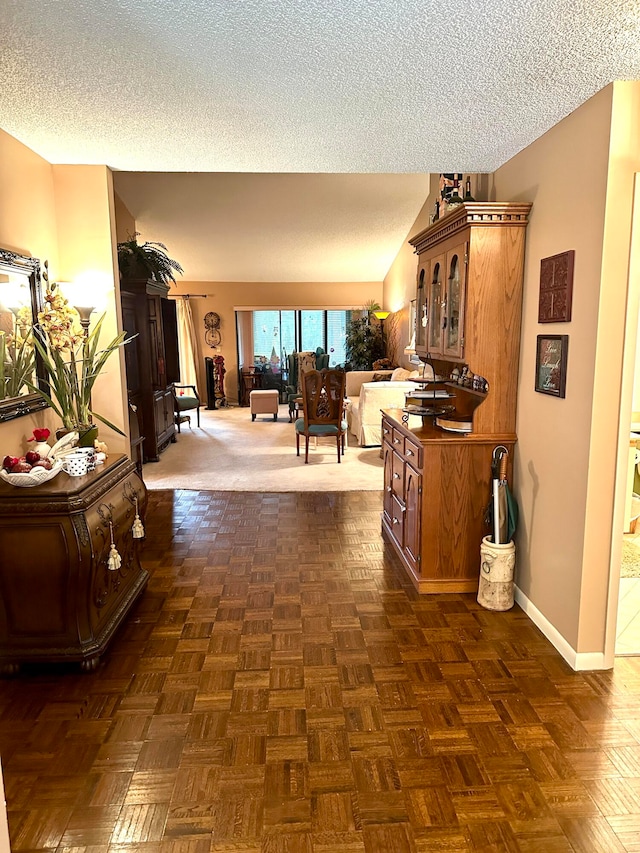 corridor with lofted ceiling, a textured ceiling, and dark parquet floors