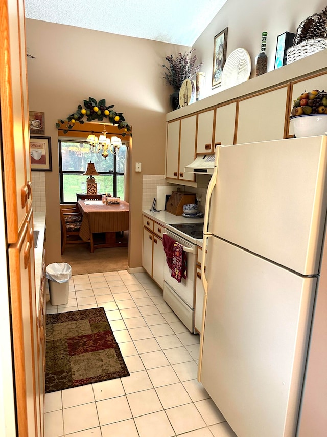 kitchen with white appliances, light tile patterned flooring, vaulted ceiling, white cabinets, and exhaust hood