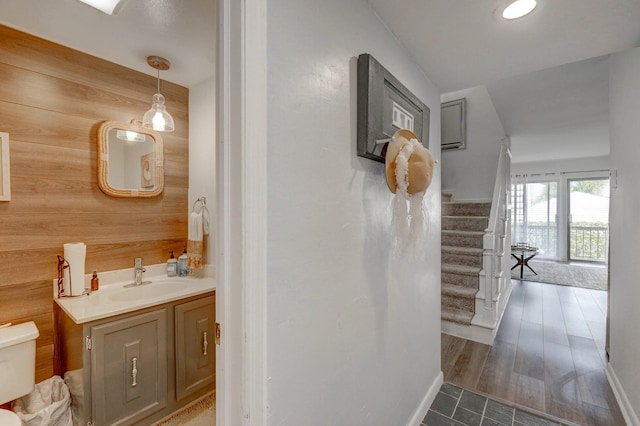 bathroom featuring vanity, hardwood / wood-style floors, toilet, and wooden walls