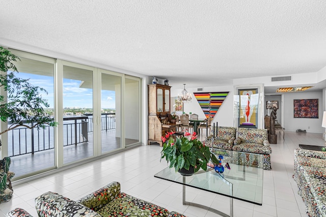 living room with a water view, a textured ceiling, and light tile patterned floors