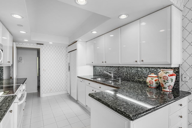 kitchen featuring dark stone counters, white appliances, white cabinetry, and sink