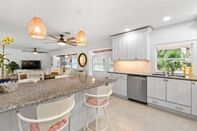 8045 W Lake Dr, Lake Clarke Shores, FL 33406 - kitchen with stainless steel dishwasher, a sink, a breakfast bar area, white cabinetry, and light stone countertops