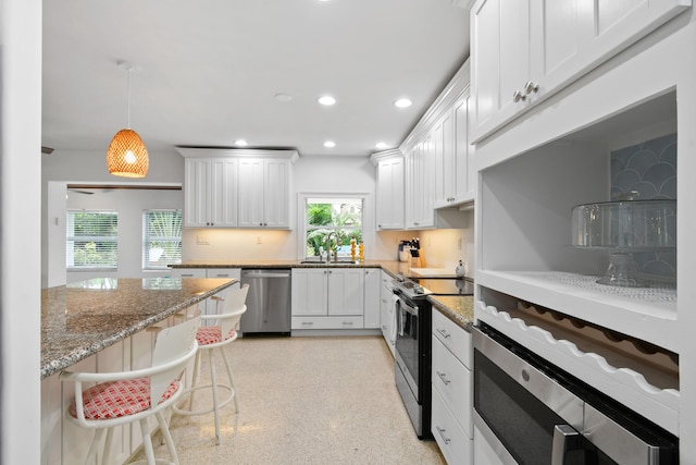 8045 W Lake Dr, Lake Clarke Shores, FL 33406 - kitchen with stainless steel dishwasher, electric stove, white cabinets, light stone counters, and recessed lighting