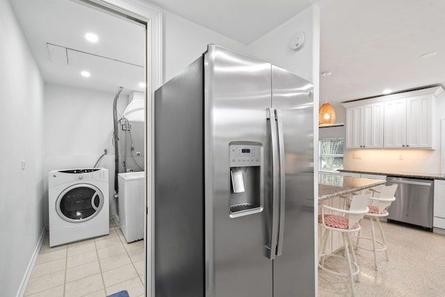8045 W Lake Dr, Lake Clarke Shores, FL 33406 - kitchen featuring stainless steel appliances, white cabinetry, light stone countertops, washer and clothes dryer, and a breakfast bar area
