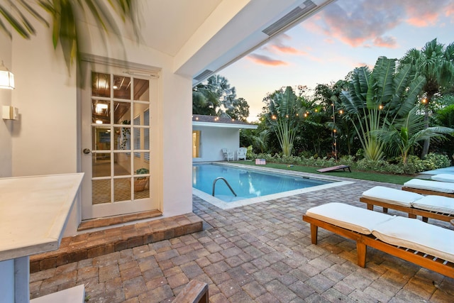 8045 W Lake Dr, Lake Clarke Shores, FL 33406 - pool at dusk with a patio and an outdoor pool