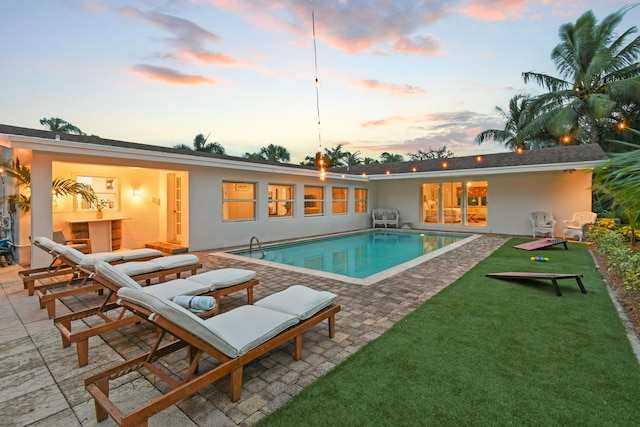 8045 W Lake Dr, Lake Clarke Shores, FL 33406 - pool at dusk with a patio, an outdoor pool, and a lawn